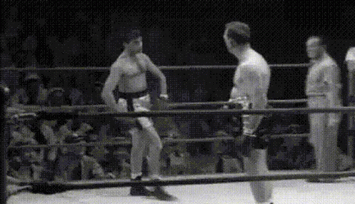 Two Men Are Fighting In A Boxing Ring With A Referee In The Background . GIF