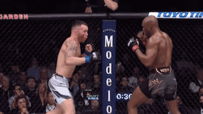 Two Men Are Fighting In A Boxing Ring With A Sign That Says Modelo GIF