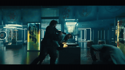 Two Men Are Fighting In A Dark Room With A Man Laying On The Floor GIF
