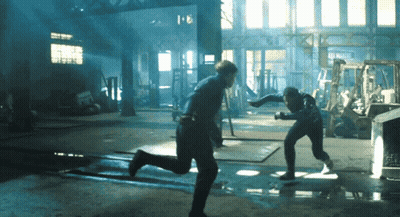 Two Men Are Fighting In A Dark Room With A Sign That Says ' Automotive ' On It GIF
