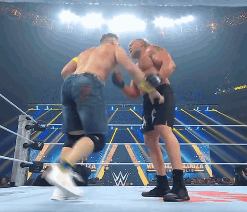 Two Men Are Fighting In A Wrestling Ring With A W Logo On The Ring GIF