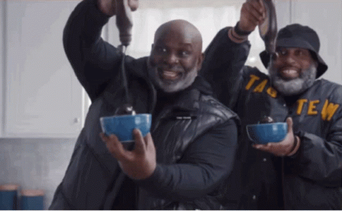 Two Men Are Holding Bowls Of Food And One Of Them Has The Word Taste On His Jacket GIF
