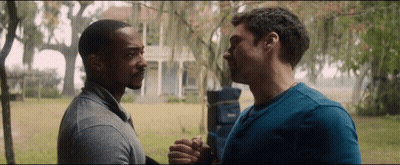 two men are holding hands in front of a house