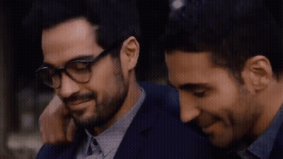 Two Men Are Hugging Each Other And One Of Them Is Wearing Glasses And A Bracelet . GIF