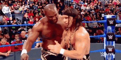 Two Men Are Hugging Each Other In A Wrestling Ring In Front Of A Crowd . GIF