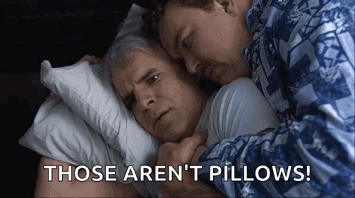 Two Men Are Hugging Each Other In Bed With The Words `` Those Aren 'T Pillows '' Written In The Corner . GIF