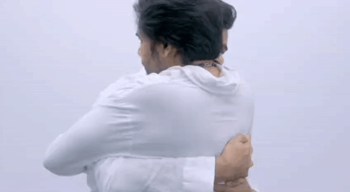 Two Men Are Hugging Each Other With Their Arms Around Each Other . GIF