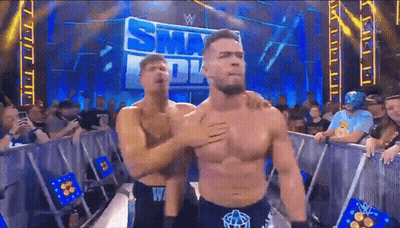 Two Men Are Hugging In Front Of A Sign That Says ' Smackdown ' GIF