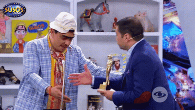 Two Men Are Hugging In Front Of A Sign That Says Susos GIF