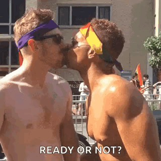 Two Men Are Kissing Each Other In Front Of A Crowd At A Parade . GIF
