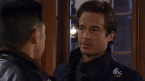 Two Men Are Kissing In Front Of A Window . GIF