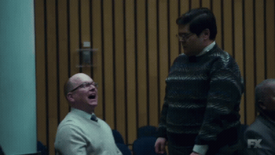 Two Men Are Laughing In Front Of A Wall With Fx On It GIF
