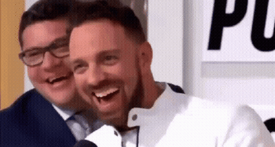 Two Men Are Laughing Together In Front Of A Microphone While Sitting Next To Each Other . GIF