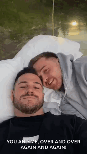 Two Men Are Laying On A Bed With Their Heads Together And Smiling . GIF