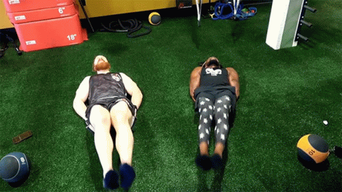 Two Men Are Laying On The Floor With One Wearing A Shirt That Says ' Sdf ' On It GIF