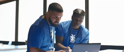 Two Men Are Looking At A Laptop Computer . GIF