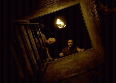 Two Men Are Looking Out A Window At A Torch . GIF