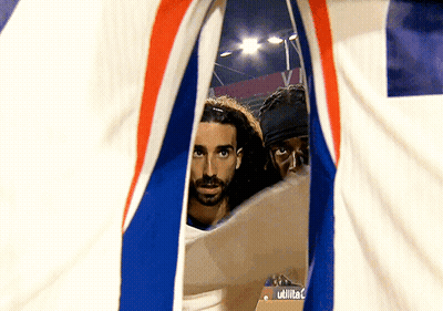 Two Men Are Looking Through A Hole In A Flag That Says Utilita GIF