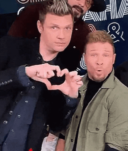 Two Men Are Making A Heart Shape With Their Hands While Posing For A Picture . GIF