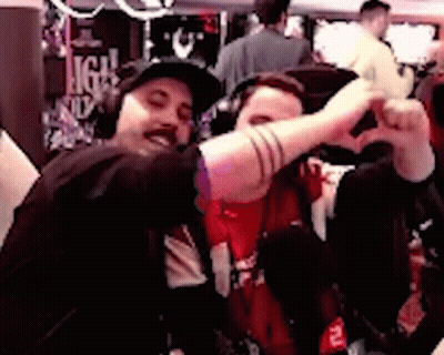 Two Men Are Making A Heart Shape With Their Hands While Sitting Next To Each Other . GIF