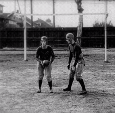 Two Men Are Playing A Game Of Football On A Field In A Black And White Photo . GIF