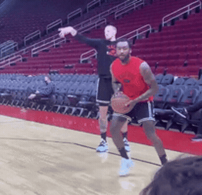 Two Men Are Playing Basketball In A Stadium With Empty Seats GIF