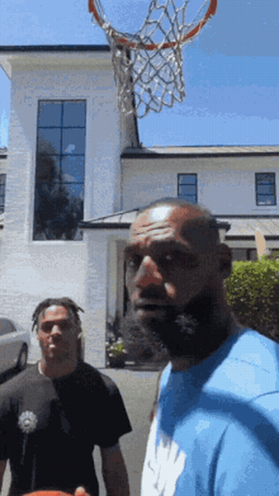 Two Men Are Playing Basketball In Front Of A Large White Building GIF