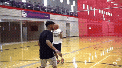 Two Men Are Playing Basketball On A Court In Front Of A Sign That Says ' Champions ' On It GIF