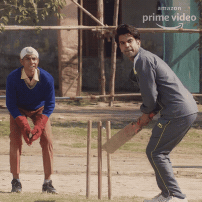 Two Men Are Playing Cricket In Front Of An Amazon Prime Video Banner GIF