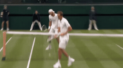 Two Men Are Playing Tennis On A Court And One Of Them Is Holding A Tennis Racquet GIF