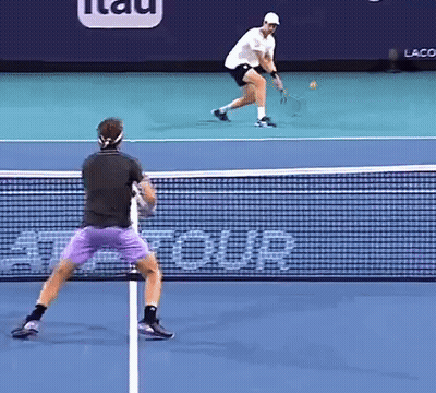 Two Men Are Playing Tennis On A Court With A Sign That Says Tour GIF