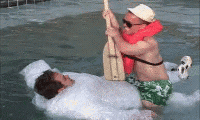 Two Men Are Playing With A Paddle In A Swimming Pool . GIF