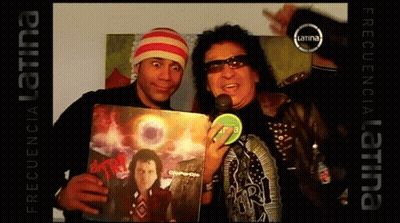 Two Men Are Posing For A Picture And One Of Them Is Holding A Record That Says ' Frequency Latina ' On The Bottom GIF