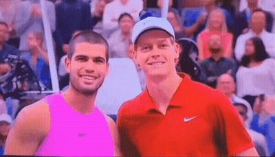 Two Men Are Posing For A Picture In Front Of A Crowd . One Is Wearing A Pink Tank Top . GIF