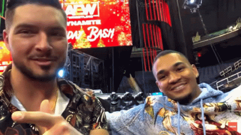 Two Men Are Posing For A Picture In Front Of A Sign That Says Aew Day Bash GIF