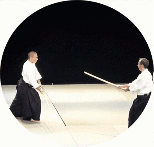 Two Men Are Practicing Martial Arts With Swords In A Circle GIF