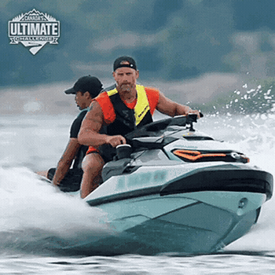 Two Men Are Riding A Jet Ski In The Water With The Ultimate Challenge Logo On The Bottom GIF