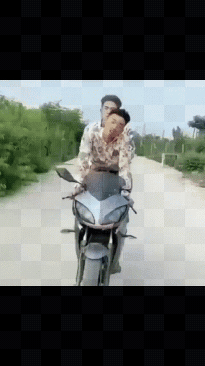 Two Men Are Riding A Motorcycle On A Road GIF