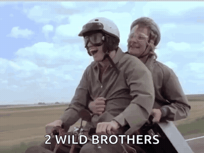 Two Men Are Riding A Motorcycle With A Saw On Their Backs . GIF