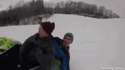 Two Men Are Riding A Sled Down A Snowy Hill GIF