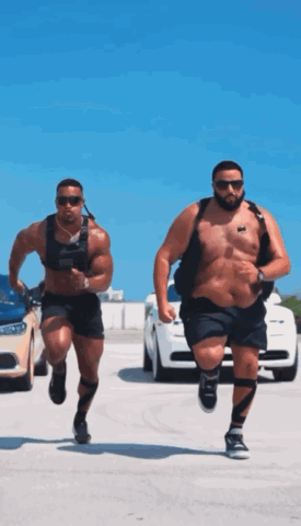 Two Men Are Running In A Parking Lot And One Has A Sticker On His Chest That Says ' A ' On It GIF