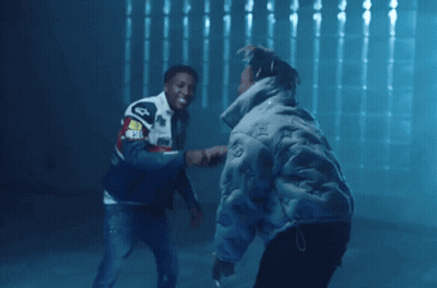 Two Men Are Shaking Hands In A Dark Room And One Has A Jacket That Says ' Audi ' On The Back GIF
