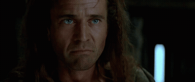 Two Men Are Shaking Hands In Front Of A Crowd In A Dark Room . GIF