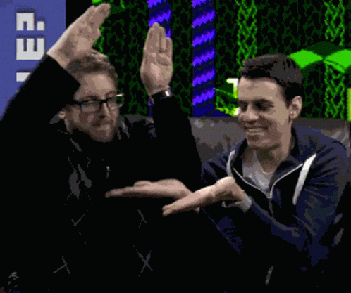 Two Men Are Shaking Hands In Front Of A Sign That Says T. GIF