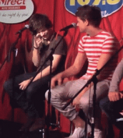 Two Men Are Singing Into Microphones In Front Of A Sign That Says 102.9 GIF