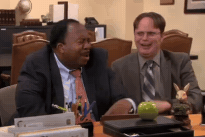 Two Men Are Sitting At A Desk With A Green Apple On It GIF