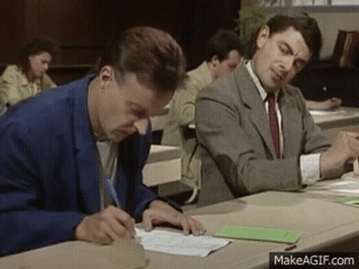 Two Men Are Sitting At A Desk Writing On A Piece Of Paper In A Classroom . GIF