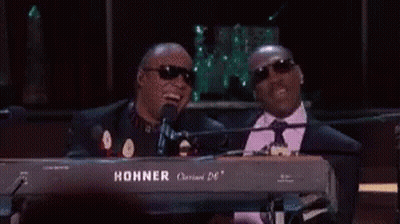 Two Men Are Sitting At A Keyboard And One Of Them Is Wearing Sunglasses . GIF