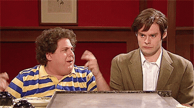 Two Men Are Sitting At A Table And One Has A Striped Shirt On GIF