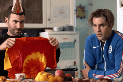 Two Men Are Sitting At A Table And One Is Wearing A Blue Nike Jacket GIF